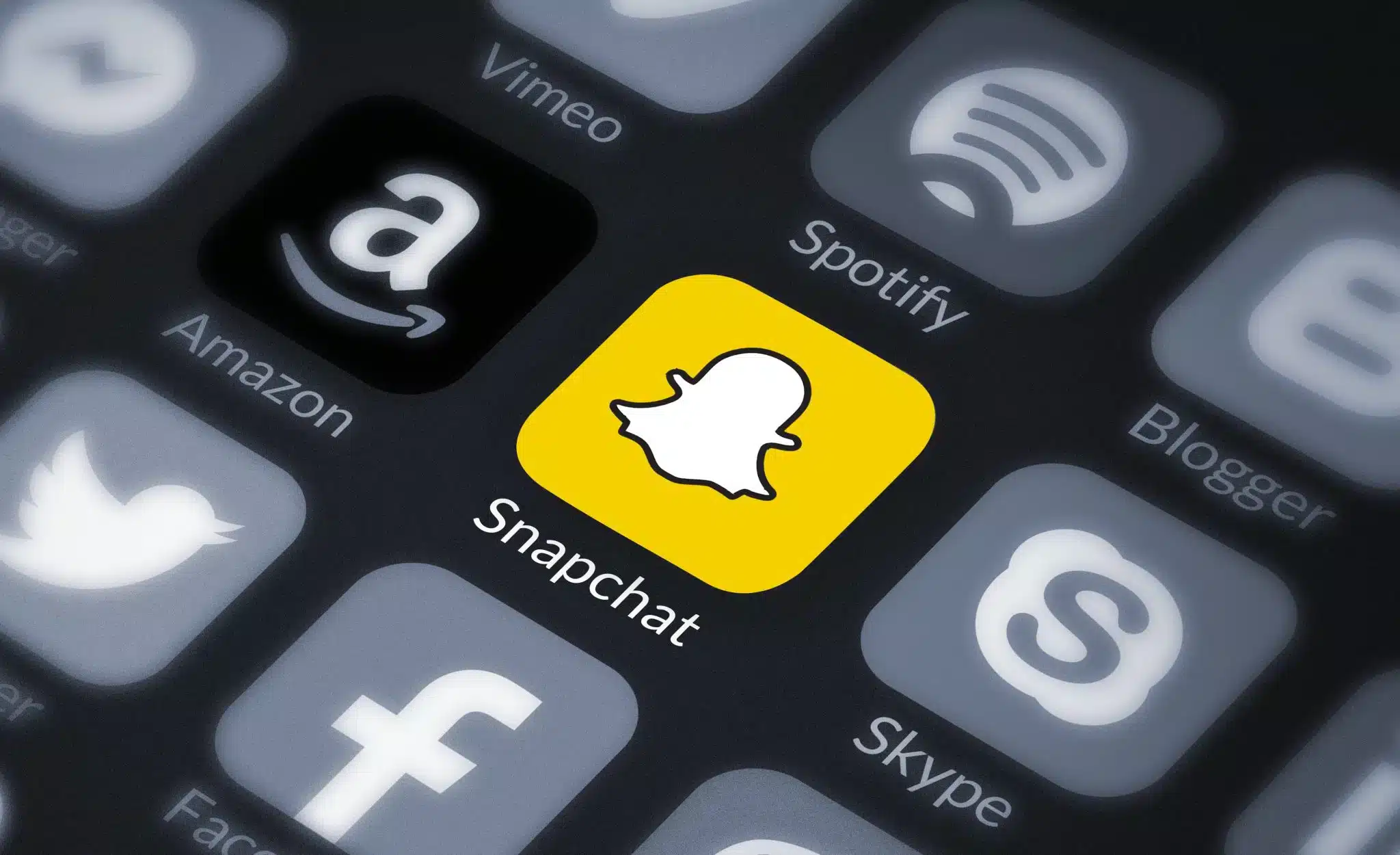 صورةٌ للعديد من التطبيقات باللون الأبيض والرماديّ يتوسطها تطبيقSnapchat 