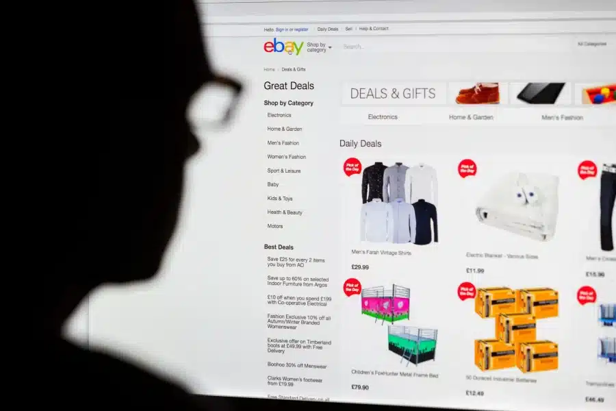 موقع EBay على شاشة حاسوب ويظهر أمامَها ظلٌّ لوجه شخص يطالع الشاشة