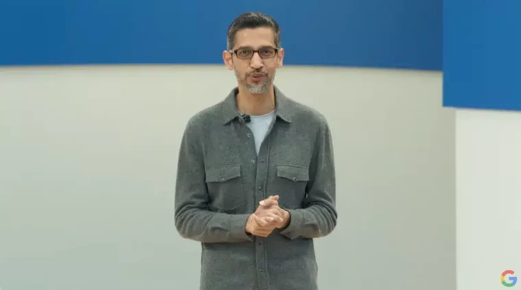 ساندر بيتشاي (Sundar Pichai) يرتدي قميصاً زيتياً ويضع نظارات ويضم كفيه إلى بعضهما وخلفه جدار أزرق وأبيض