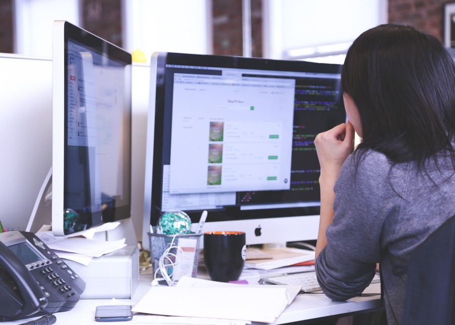 Woman working on two computer monitors