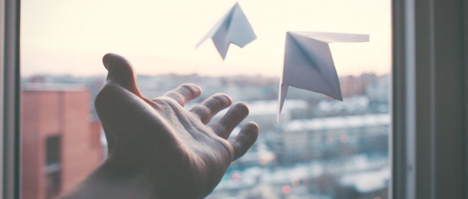 hand launching paper airplanes out of window