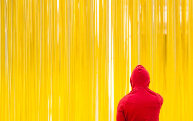 a-woman-standing-in-front-of-a-rainbow-colored-wall-with-her-shadow-on