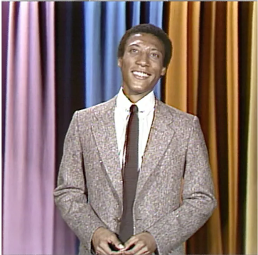 Byron Allen in front of a curtain