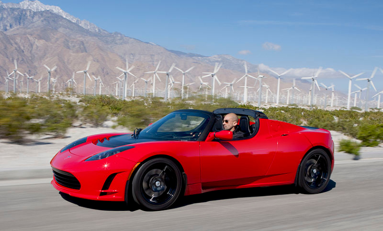 tesla roadster in front of windmills