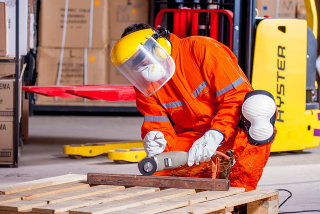 A man wearing protective gear using a multitool on a wood pellet. 