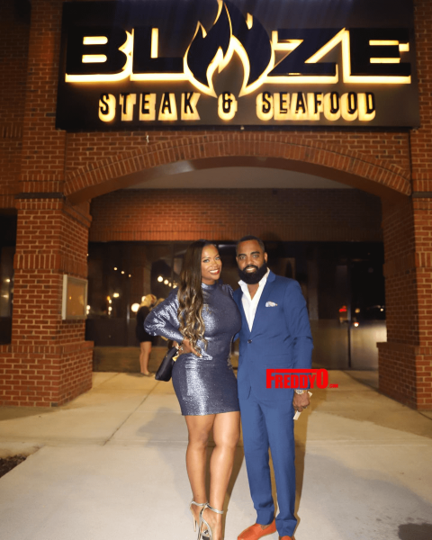 Kandi Burruss and her husband in front of a restaurant