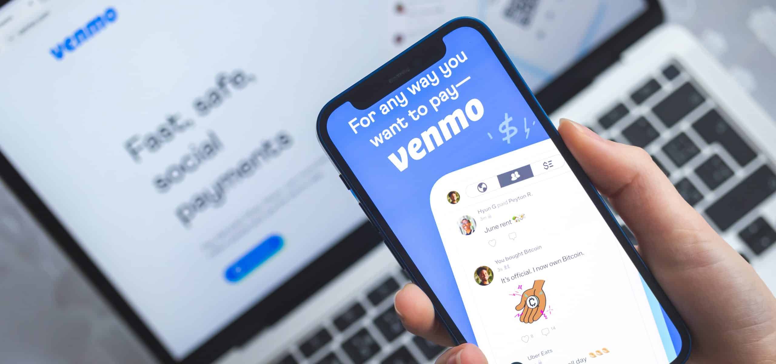 venmo on a phone with a laptop in the background