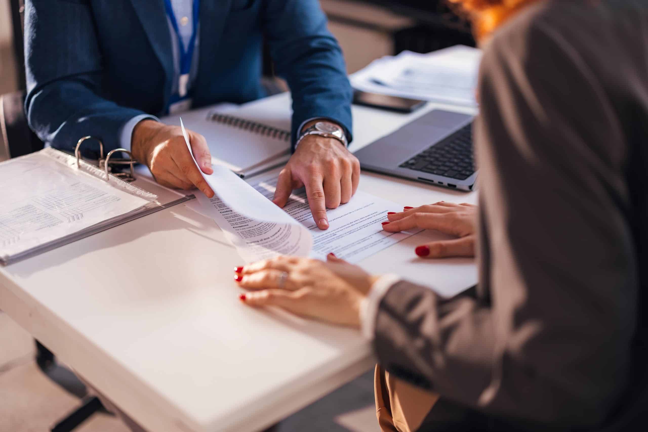 2 people sitting at a desk going over papers