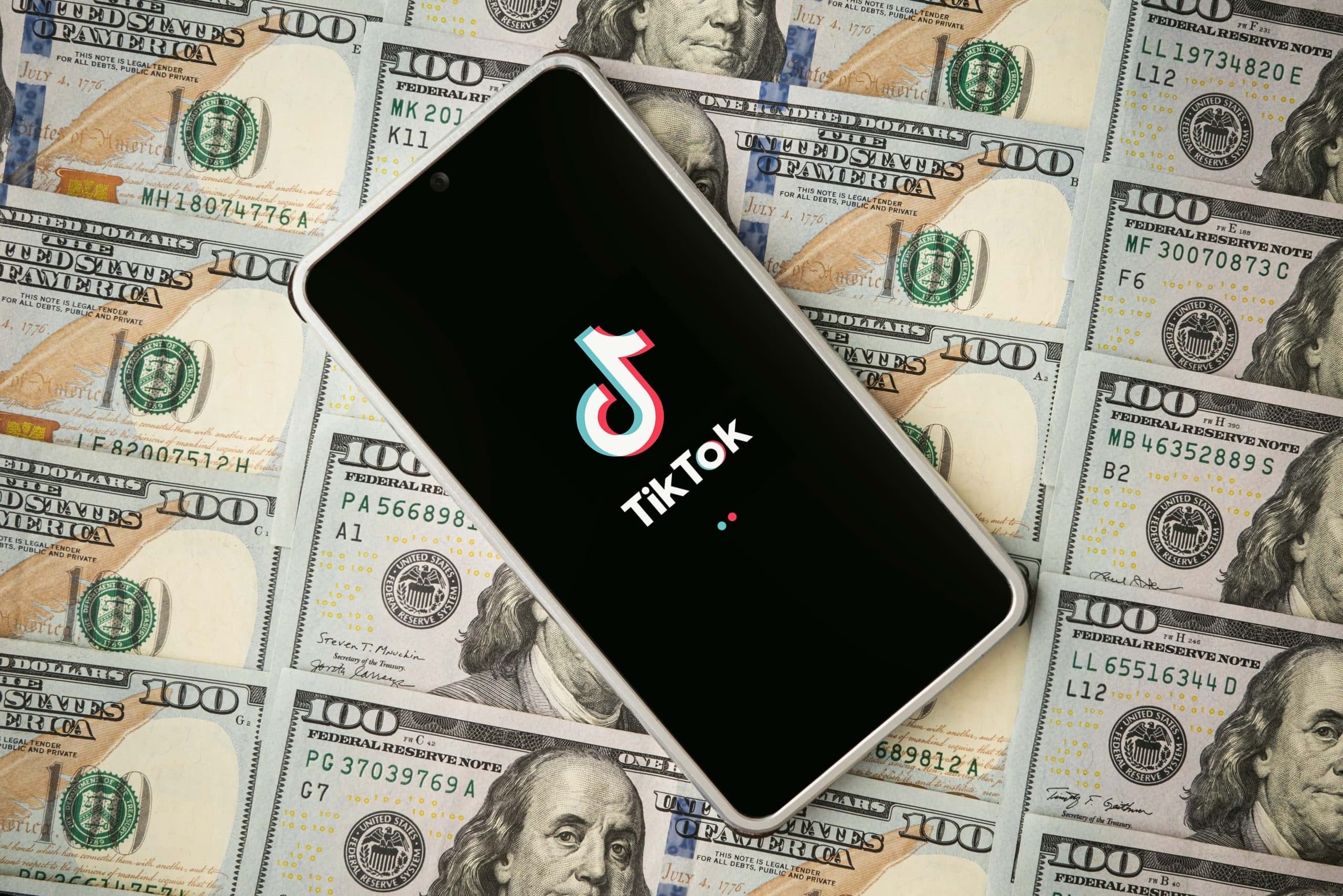 Phone with TikTok logo on 100 dollar bills